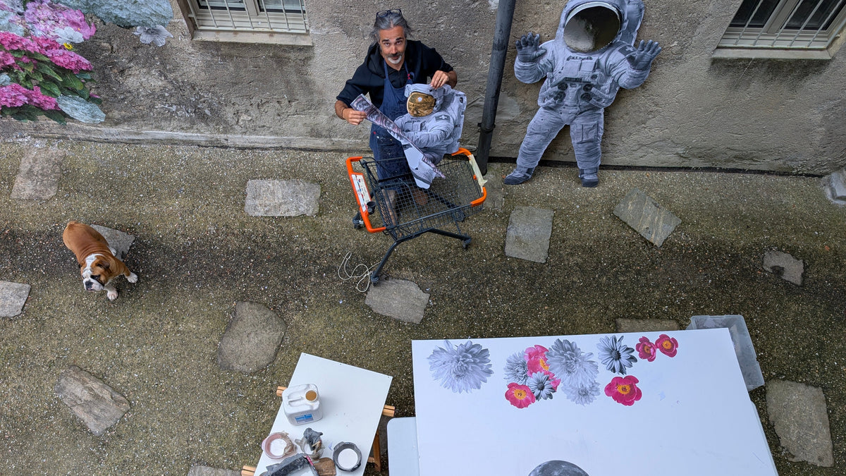 Veduta dall'alto dell'atelier di Yuri Catania a Rovio, Canton Ticino, con opere su carta, sculture di astronauti e il giardino fiorito.